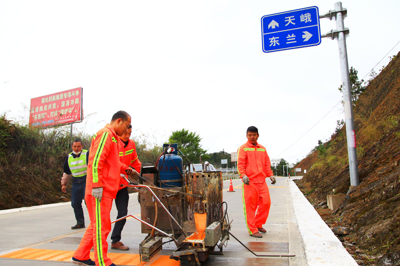 養(yǎng)路工人在國(guó)道243線鳳山縣境路段施劃路面標(biāo)線（河池公路發(fā)展中心 韋昌學(xué)  攝）
