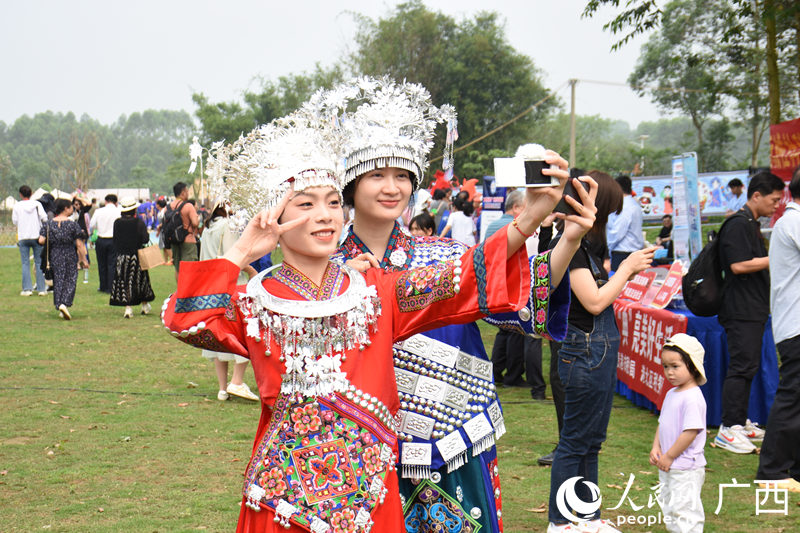 游客穿著少數(shù)民族特色服飾在景點(diǎn)打開(kāi)拍照。人民網(wǎng) 王功孝攝