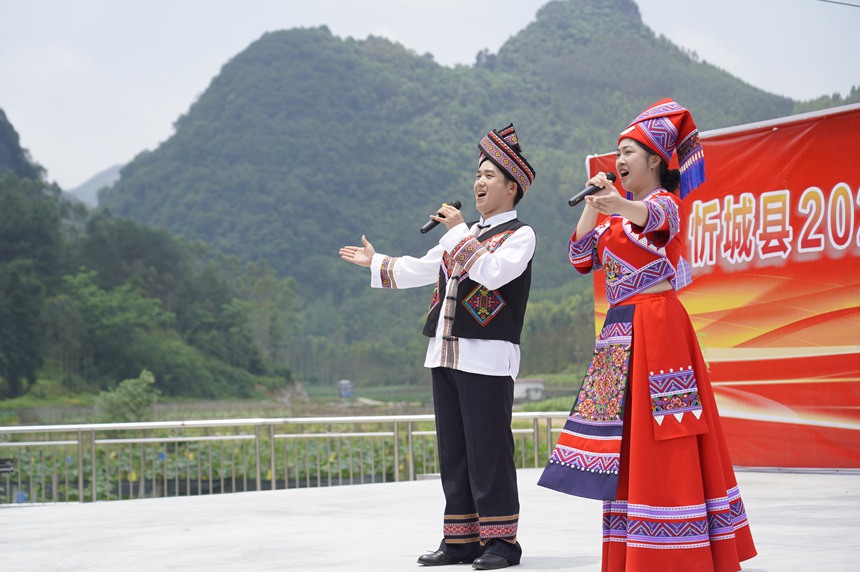 5月17日，在忻城縣大塘鎮(zhèn)六安村開展社會科學普及活動周暨全民藝術普及月基層文藝演出活動，圖為社科普及志愿者為群眾演唱本土原創(chuàng)歌曲《我在忻城等你來》