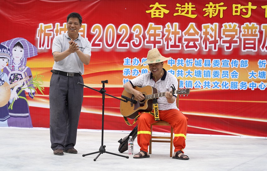 5月17日，在忻城縣大塘鎮(zhèn)六安村開(kāi)展社會(huì)科學(xué)普及活動(dòng)周暨全民藝術(shù)普及月基層文藝演出活動(dòng)。圖為社科普及志愿者為六安村群眾演繹自創(chuàng)小品