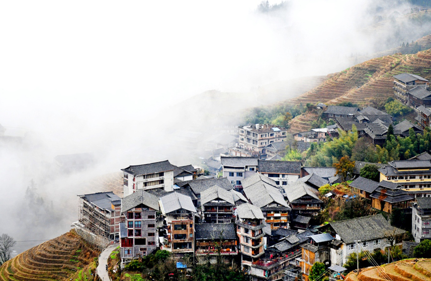 層層疊疊的梯田和錯落有致的吊腳樓在云海間若隱若現(xiàn)