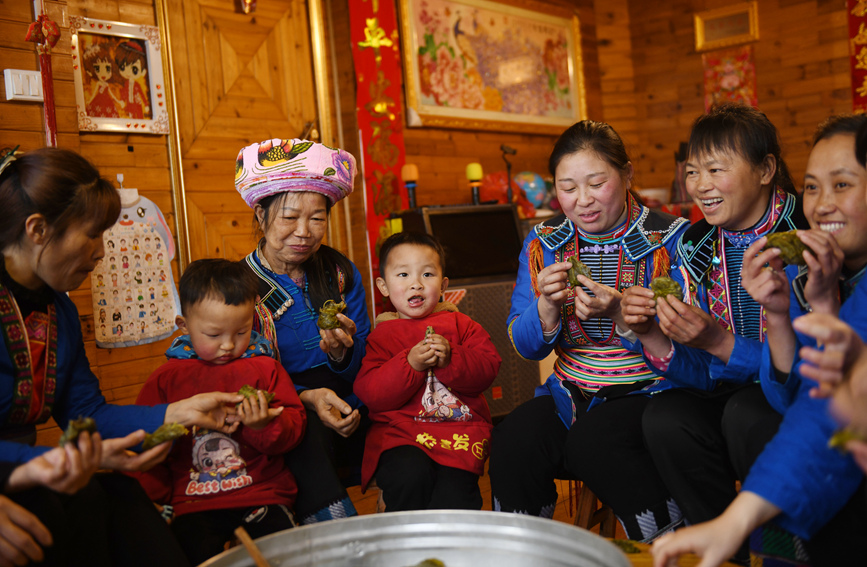 瑤族村民圍坐在一起品嘗艾粑。潘志祥攝