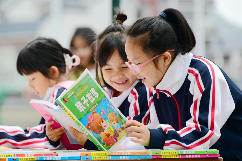 小學生在流動圖書車前閱讀圖書。