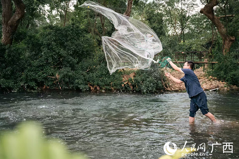 游客在靈渠體驗撒網(wǎng)捕魚。人民網(wǎng)記者 嚴(yán)立政攝