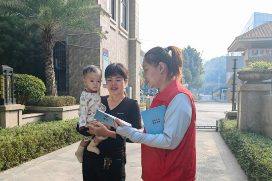 圖為：志愿者向轄區(qū)居民宣傳文明行為基本知識(shí)