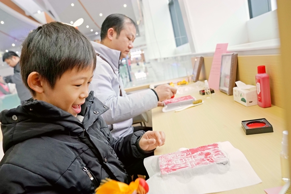 春運首日，旅客在玉林北站高鐵讀書驛站體驗非遺拓印。白玨翠攝