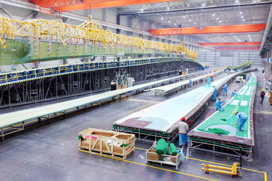 中車百色新能源裝備產(chǎn)業(yè)項(xiàng)目葉片生產(chǎn)車間，工人在生產(chǎn)線上忙碌的檢查設(shè)備。