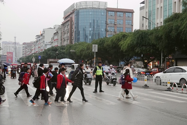 交警護(hù)航小學(xué)生集體安全通過(guò)馬路。陳君雨攝
