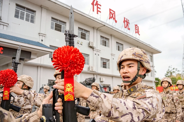 老兵將手中鋼槍交于新兵。