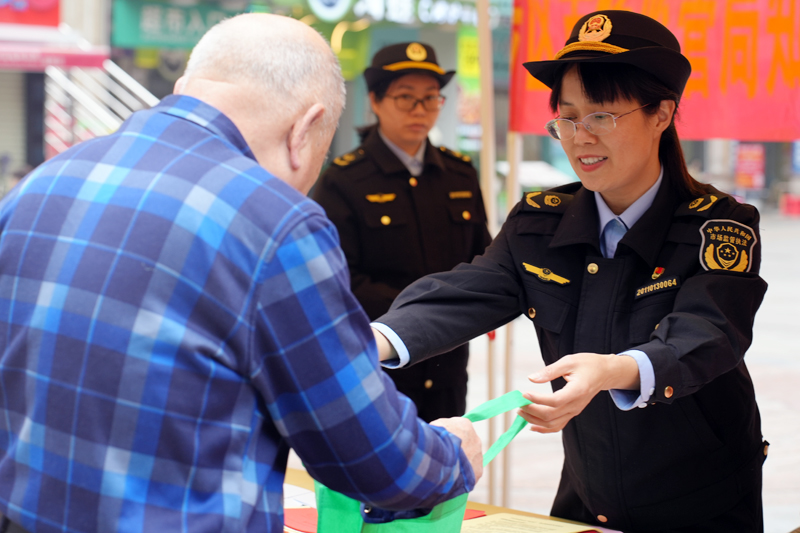 工作人員正在向市民發(fā)放宣傳資料，并普及消費(fèi)維權(quán)相關(guān)知識(shí)。