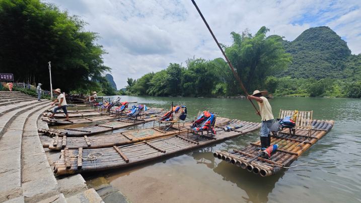 行進中國丨遇龍河上，“智慧筏”撐開新景中午12點，桂林市陽朔縣遇龍河景區(qū)筏工蔣受乾將竹筏停靠在驥馬碼頭旁，仔細擦拭竹筏上的座椅。隨著游客登筏，他的服務里程、安全記錄與游客評價，都將通過無形的數(shù)據(jù)，實時匯入景區(qū)“智慧大腦”的江河。