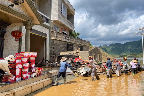 10月4日，在谷留村八屯，村干與村民在積水中有序傳遞物資。黃舒可攝