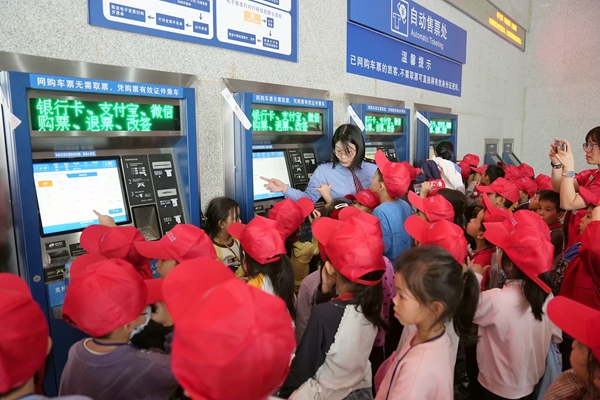 鐵路職工在玉林站售票廳給研學(xué)學(xué)生講解自助售票操作流程。何毅攝